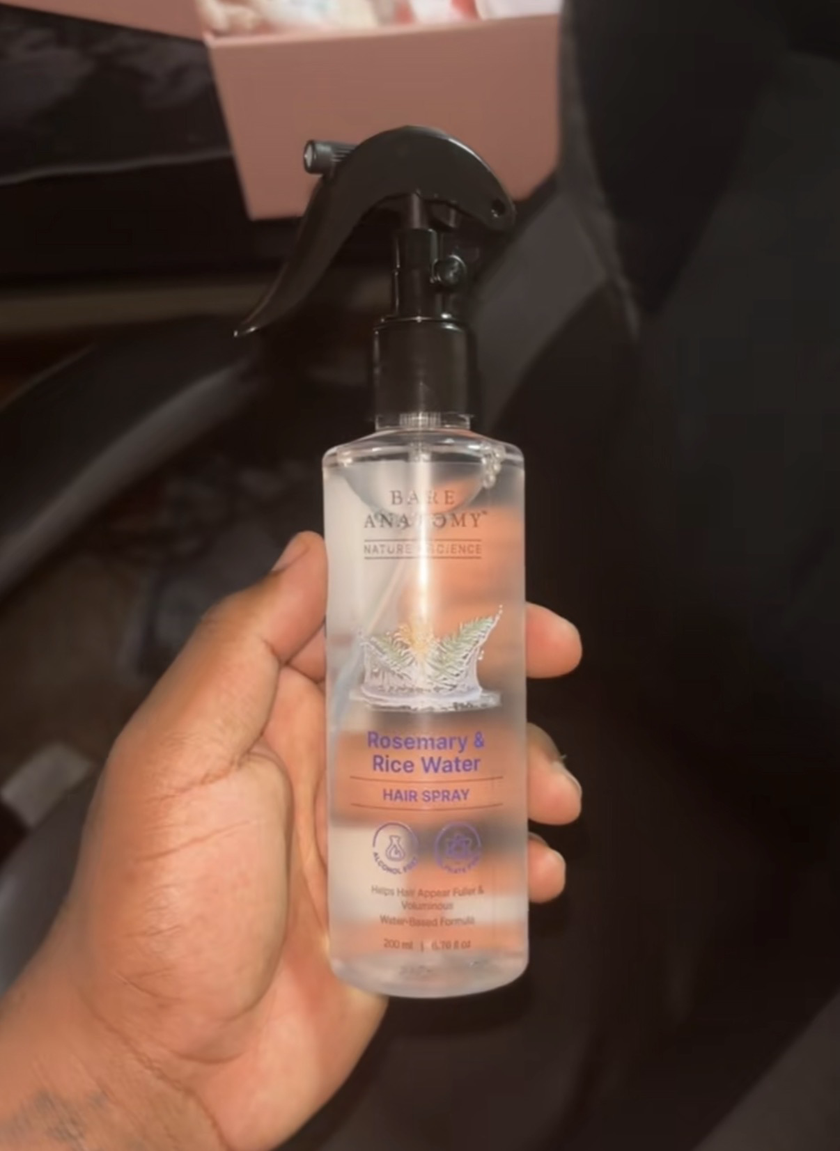 Amara O. holding her Rosemary Mist hair spray